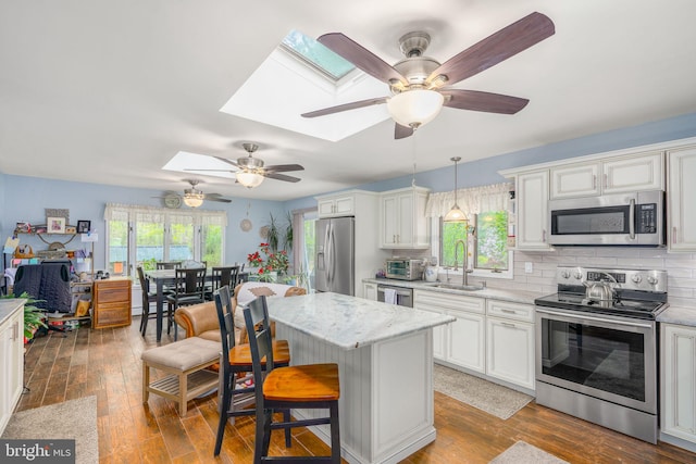 kitchen featuring decorative light fixtures, dark hardwood / wood-style flooring, stainless steel appliances, and a skylight