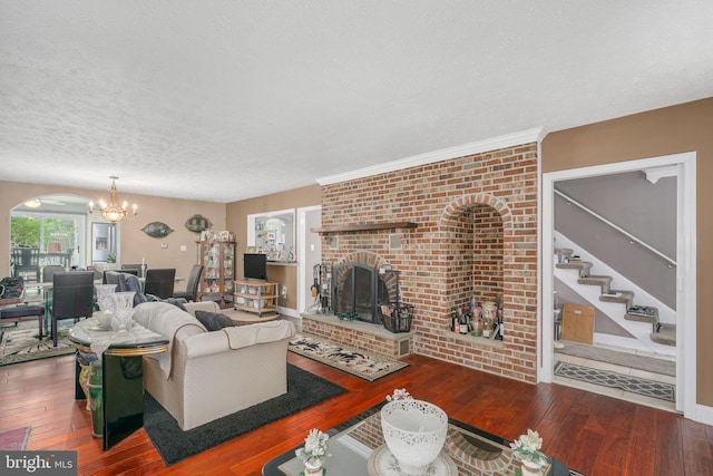 living room featuring an inviting chandelier, dark hardwood / wood-style flooring, a textured ceiling, and a brick fireplace