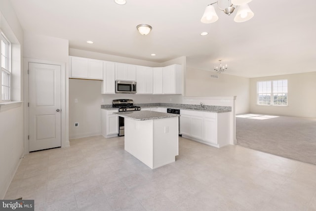 kitchen with white cabinetry, a center island, stainless steel appliances, and a notable chandelier