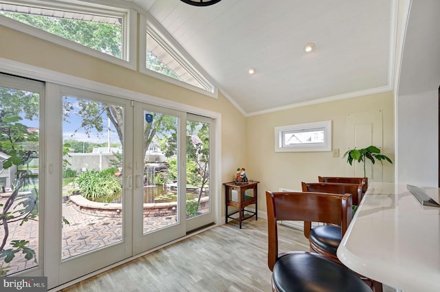 dining space with vaulted ceiling, ornamental molding, french doors, and light wood-type flooring