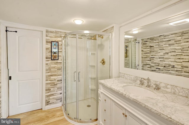 bathroom featuring vanity with extensive cabinet space, hardwood / wood-style floors, and a shower with door