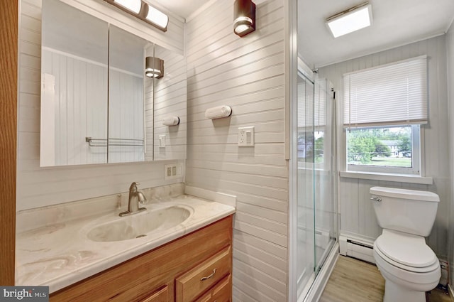 bathroom with a baseboard radiator, toilet, wood-type flooring, wooden walls, and vanity