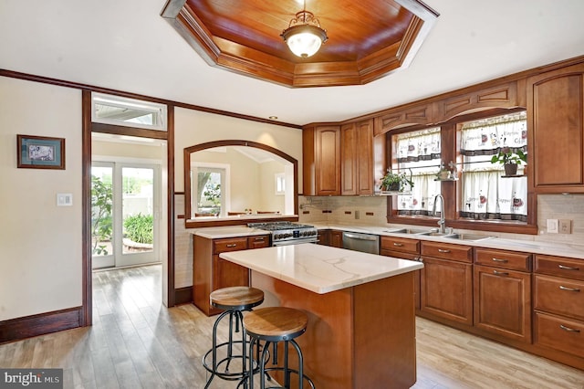 kitchen with a center island, light hardwood / wood-style floors, appliances with stainless steel finishes, backsplash, and sink