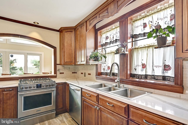 kitchen featuring light hardwood / wood-style floors, crown molding, stainless steel appliances, sink, and tasteful backsplash