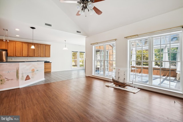 unfurnished living room with a wealth of natural light, ceiling fan, high vaulted ceiling, and hardwood / wood-style flooring