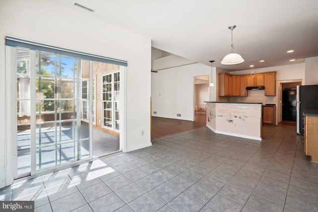 kitchen with decorative light fixtures, light tile patterned floors, and stainless steel refrigerator