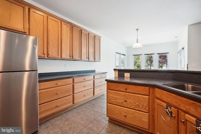 kitchen featuring tile patterned floors, decorative light fixtures, stainless steel fridge, and sink