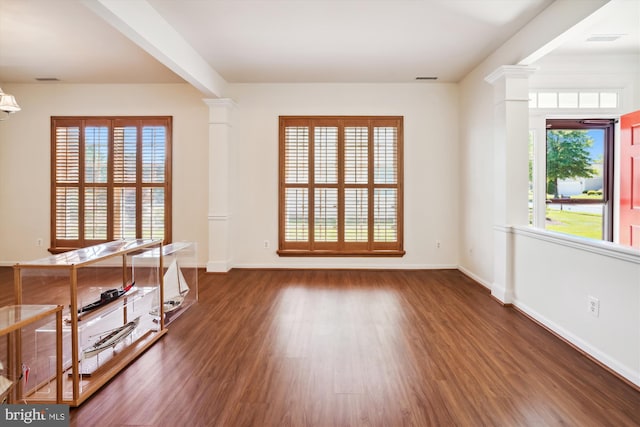 spare room with plenty of natural light, dark hardwood / wood-style floors, and decorative columns