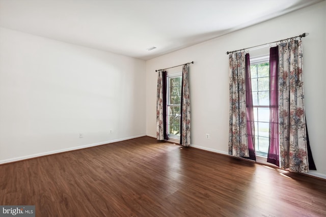 unfurnished room with dark hardwood / wood-style flooring and a healthy amount of sunlight