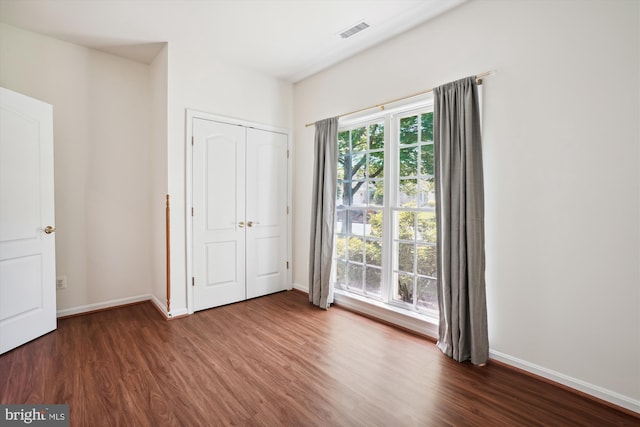 unfurnished bedroom with dark hardwood / wood-style floors and a closet