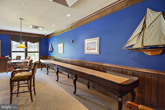 recreation room with carpet flooring, crown molding, and wood walls