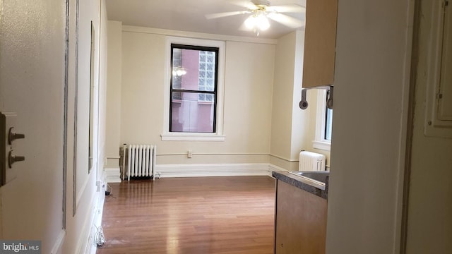 unfurnished room featuring ceiling fan, radiator heating unit, and wood-type flooring