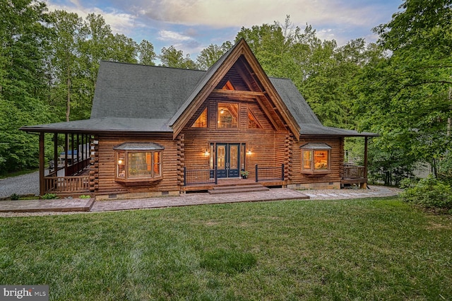 back house at dusk featuring a yard and french doors