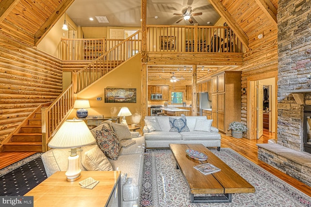 living room with hardwood / wood-style flooring, wooden ceiling, rustic walls, and high vaulted ceiling