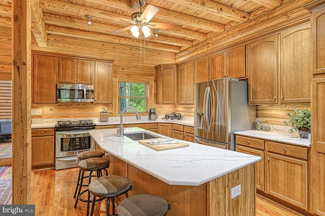 kitchen featuring light wood-type flooring, stainless steel appliances, a center island with sink, and a breakfast bar area