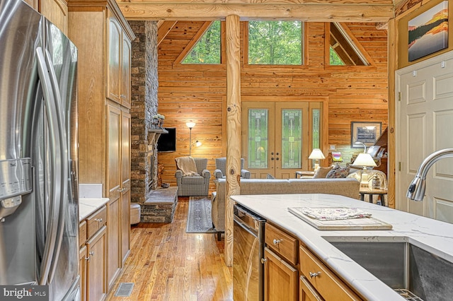 kitchen with stainless steel fridge, wooden walls, sink, and light wood-type flooring