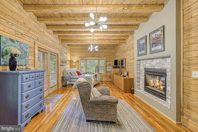 bedroom featuring wood walls, wooden ceiling, a fireplace, light hardwood / wood-style floors, and a chandelier