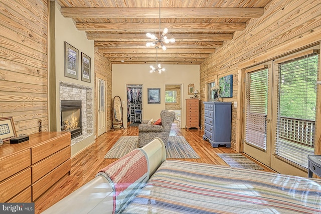 sitting room with wooden ceiling, a tile fireplace, wooden walls, light hardwood / wood-style flooring, and a notable chandelier