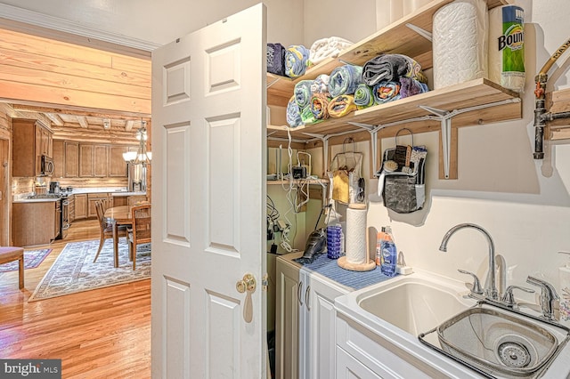 washroom featuring an inviting chandelier, sink, and light hardwood / wood-style flooring