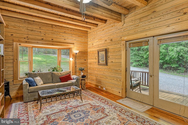 living room featuring french doors, ceiling fan, wood-type flooring, beamed ceiling, and wood walls