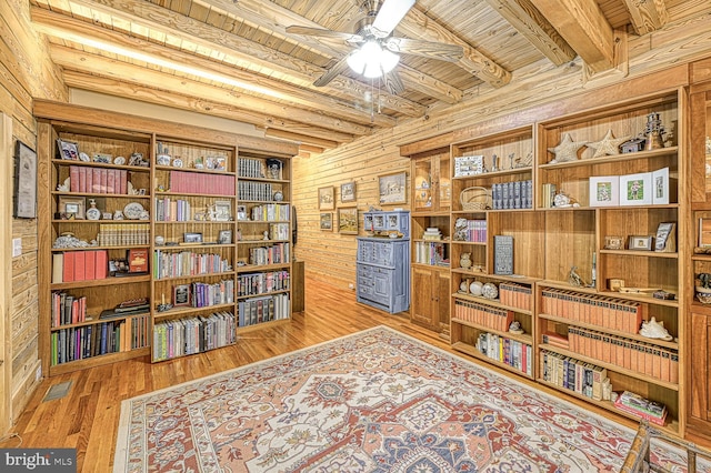 living area featuring wood ceiling, ceiling fan, beam ceiling, hardwood / wood-style flooring, and wood walls