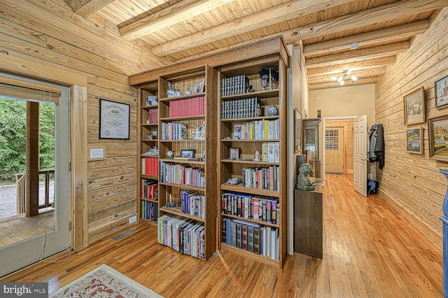 living area with beam ceiling, wooden walls, hardwood / wood-style floors, and wooden ceiling