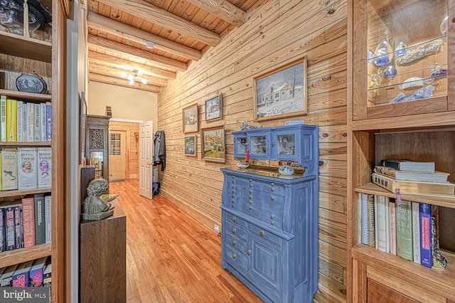 hallway featuring vaulted ceiling with beams, light hardwood / wood-style floors, wood ceiling, and wooden walls