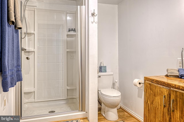 bathroom featuring hardwood / wood-style floors, toilet, and a shower with door