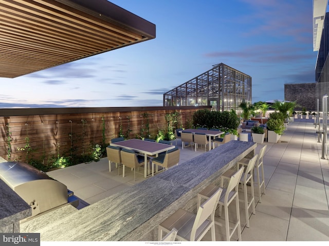 patio terrace at dusk featuring a grill and an outdoor bar