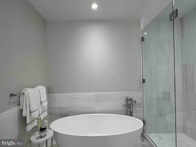 bathroom featuring separate shower and tub and tile walls