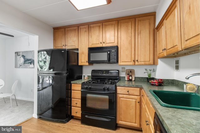 kitchen featuring black appliances, light wood-type flooring, and sink