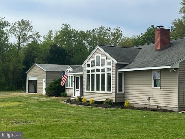 back of property with a garage and a lawn