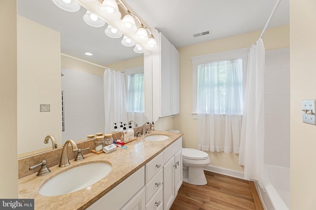 full bathroom featuring vanity, hardwood / wood-style floors, shower / bathtub combination with curtain, and toilet