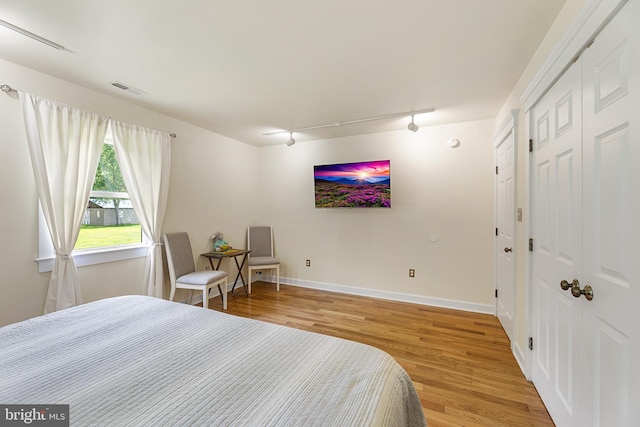 bedroom with wood-type flooring and rail lighting