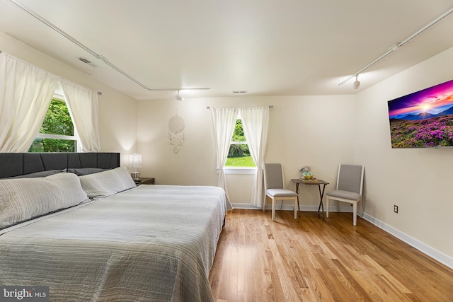 bedroom with rail lighting and light hardwood / wood-style flooring