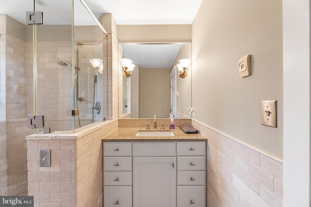 bathroom featuring vanity, a shower with door, and tile walls