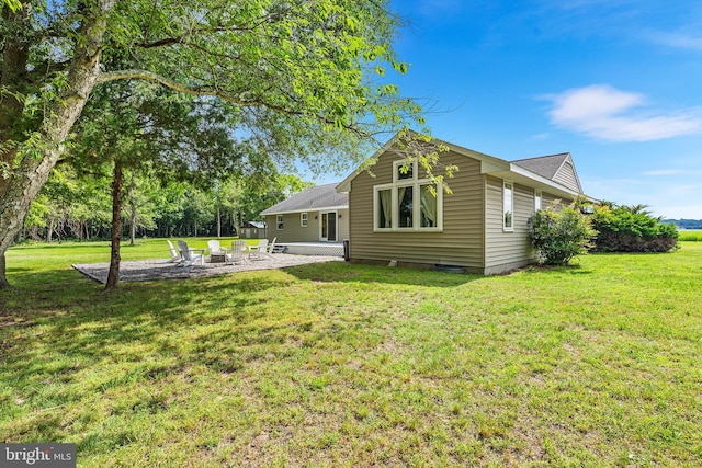 back of property featuring a lawn, a patio, and an outdoor fire pit