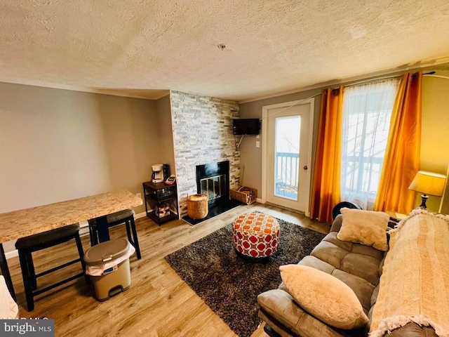 living room featuring a stone fireplace, hardwood / wood-style flooring, and a textured ceiling