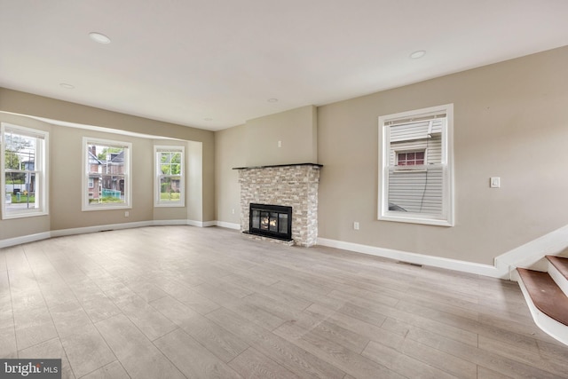 unfurnished living room with light wood-type flooring, a wealth of natural light, and a fireplace