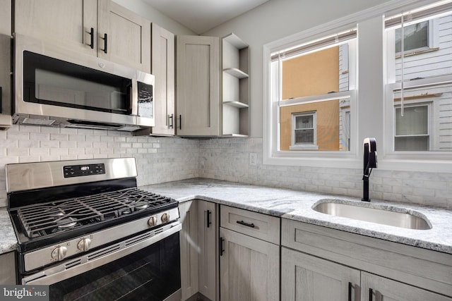 kitchen with light stone counters, sink, backsplash, and stainless steel appliances