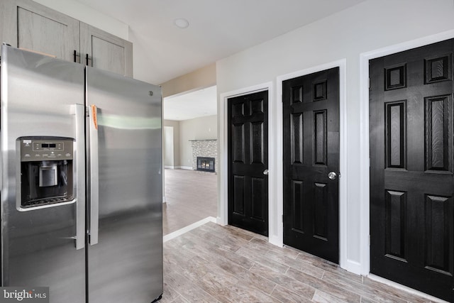 kitchen featuring light brown cabinets, stainless steel fridge, and a stone fireplace