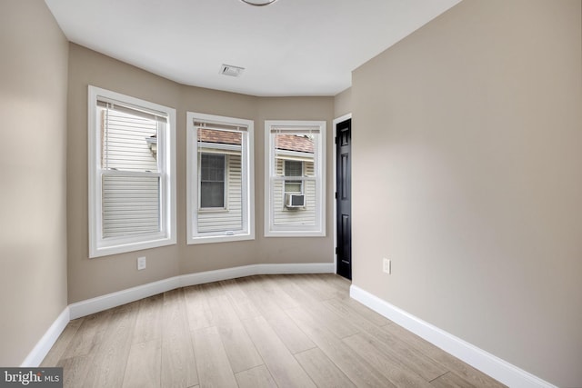 spare room featuring cooling unit and light wood-type flooring