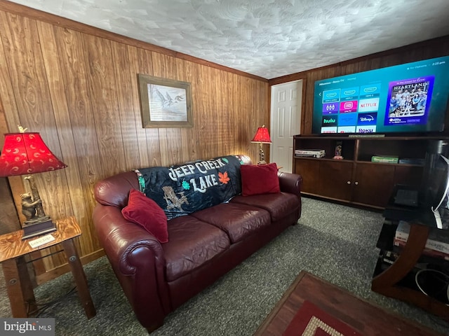 living room featuring carpet, wooden walls, and a textured ceiling