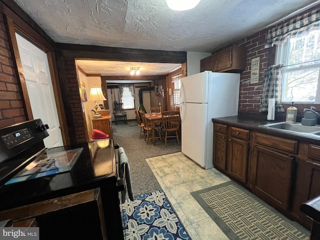 kitchen with sink, white fridge, a textured ceiling, and light colored carpet