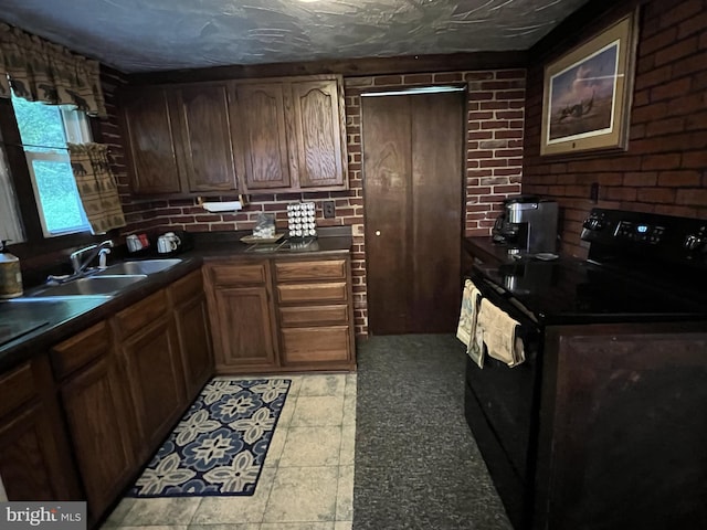 kitchen featuring brick wall, black range with electric cooktop, sink, and light tile flooring