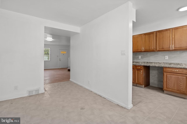 kitchen featuring light stone counters, backsplash, and light tile floors