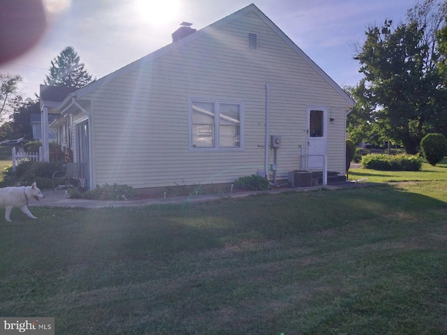 view of side of home featuring cooling unit and a lawn