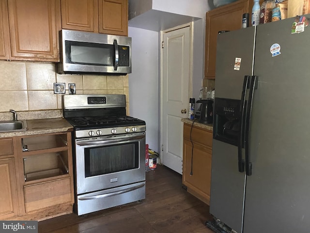 kitchen with stainless steel appliances, dark wood-type flooring, a sink, and backsplash