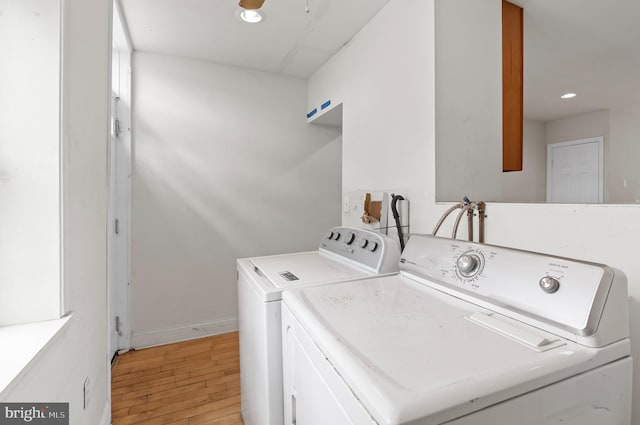 clothes washing area featuring washing machine and clothes dryer and light hardwood / wood-style flooring