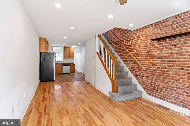 stairway with hardwood / wood-style floors and brick wall